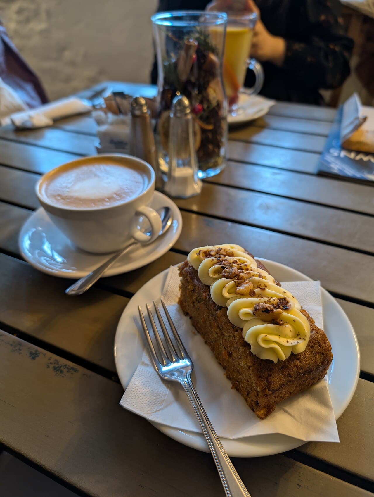 Part de carrot cake au glacage cremeux servie avec un cafe au lait