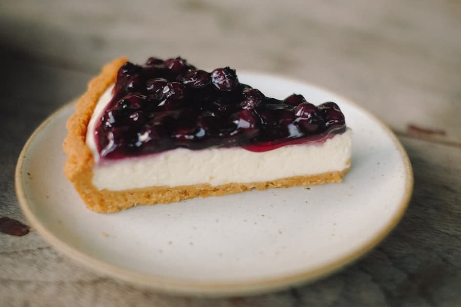Part de cheesecake cremeux nappee de fruits confits sur assiette artisanale