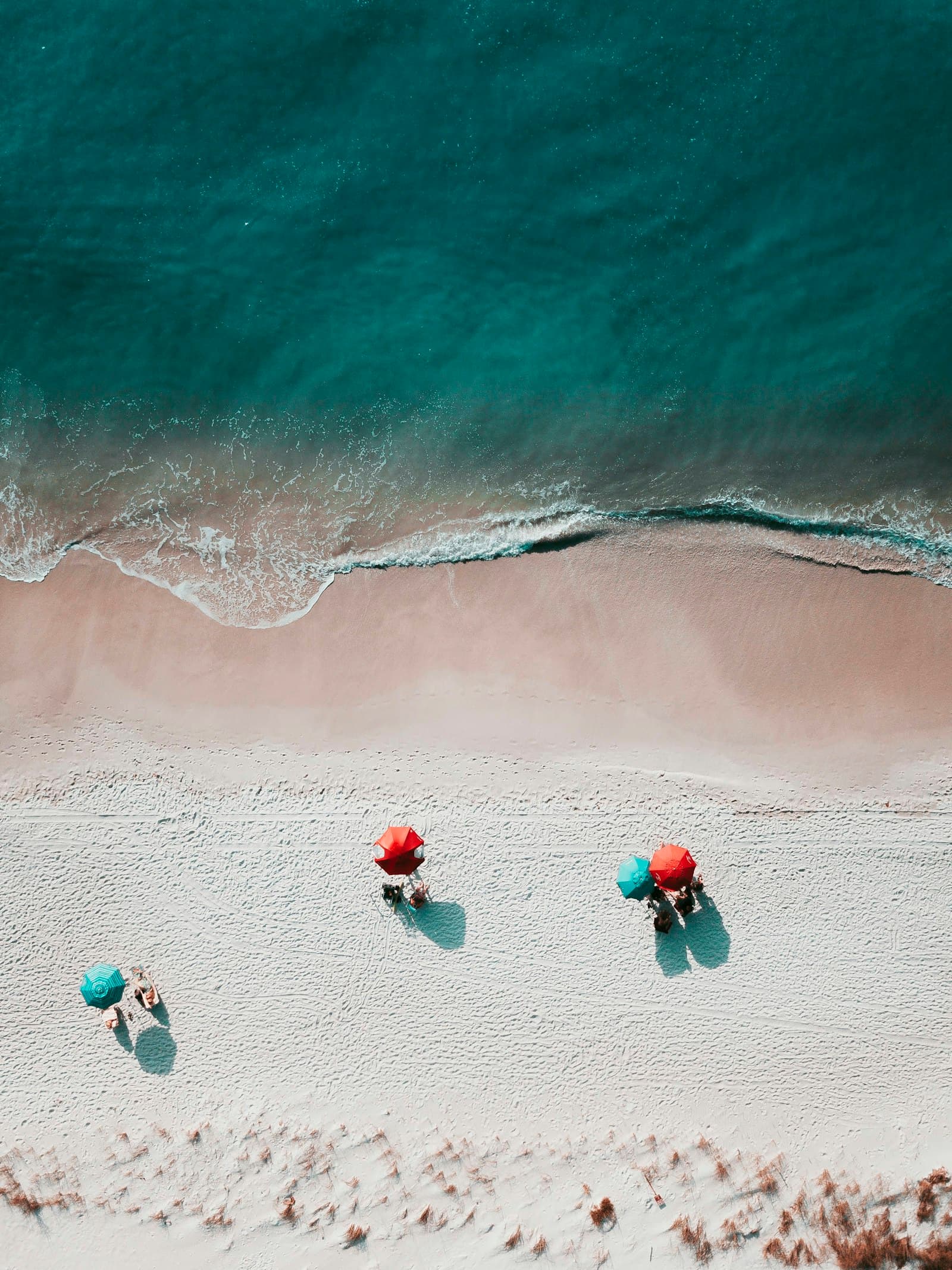 Plage vue du ciel avec parasols colorés au bord d'une mer turquoise