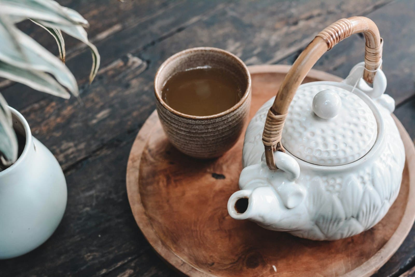 Théière artisanale et tasse de thé fumante sur un plateau en bois
