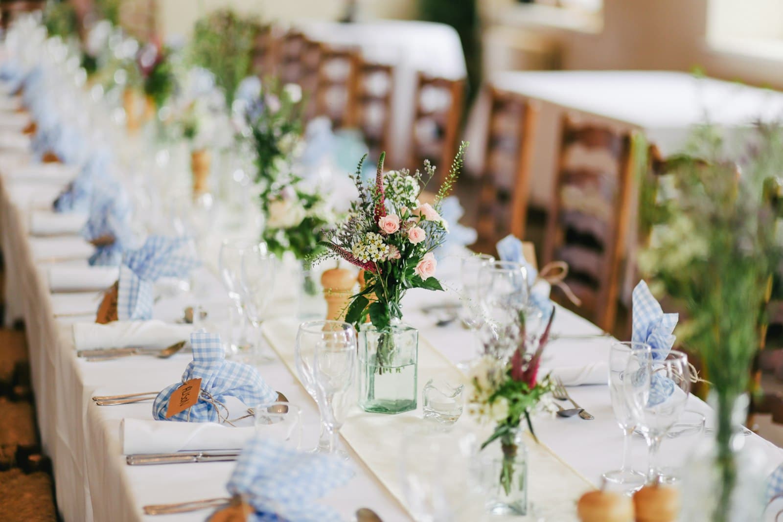 Longue table de réception dressée de fleurs et de verres pour une soirée privée