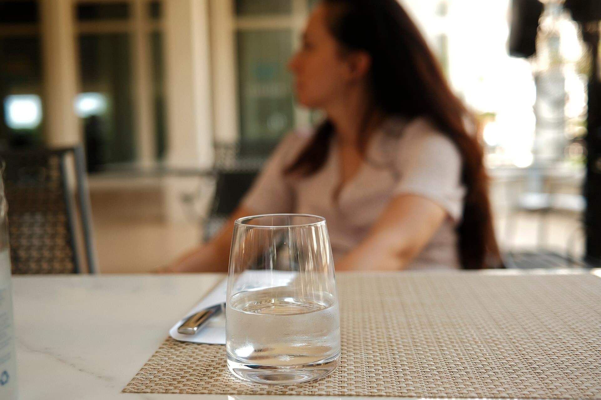 Cliente attablée en terrasse au soleil, verre à la main